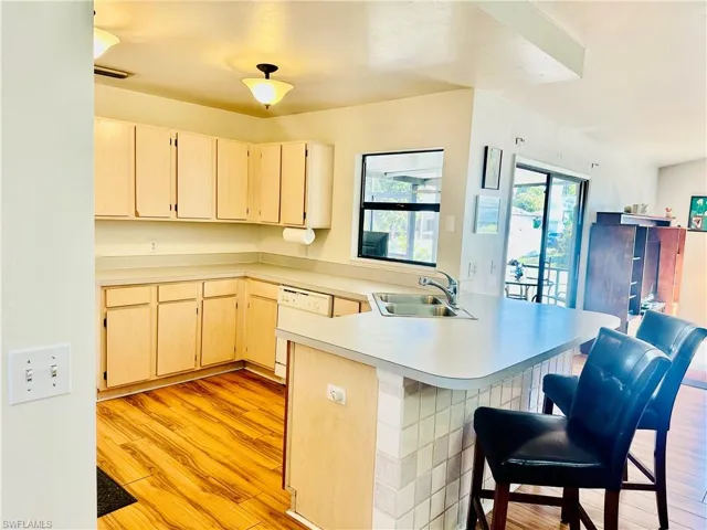 Kitchen with a peninsula, a breakfast bar area, light countertops and light laminate floors