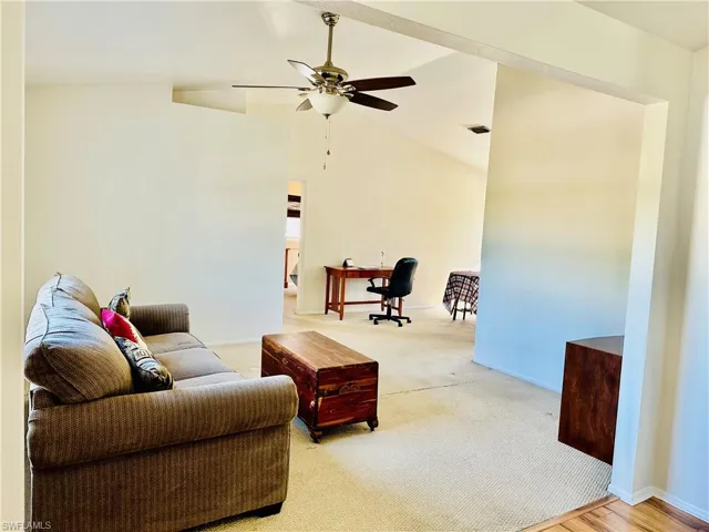 Living area featuring light colored carpet, a ceiling fan, and high vaulted ceiling