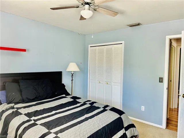 Bedroom featuring light colored carpet, ceiling fan, and a closet
