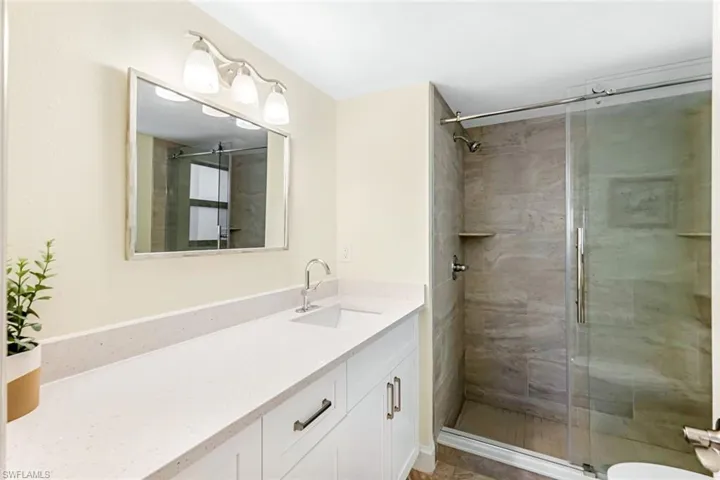 Bathroom with toilet, an enclosed shower, and vanity