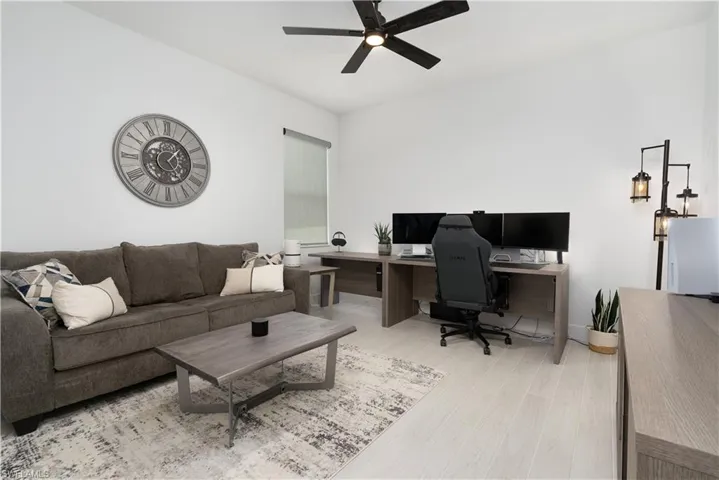 Home office with light wood-style flooring and ceiling fan
