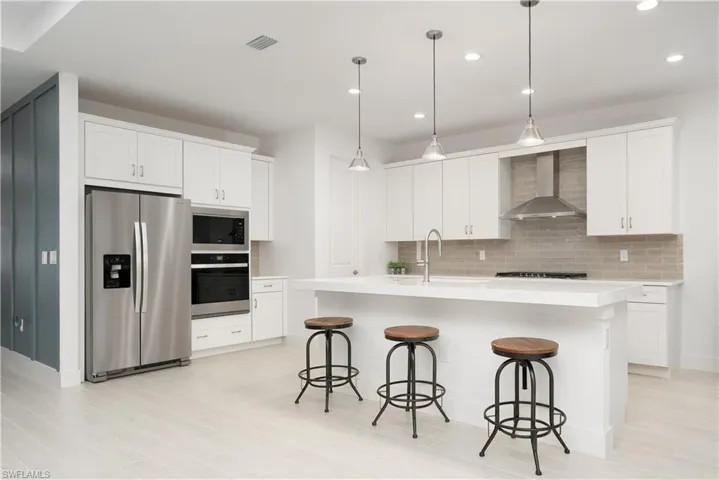 Kitchen featuring stainless steel appliances, an island with sink, white cabinetry, and recessed lighting