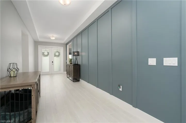 Hall with wood finished floors, a tray ceiling, and french doors