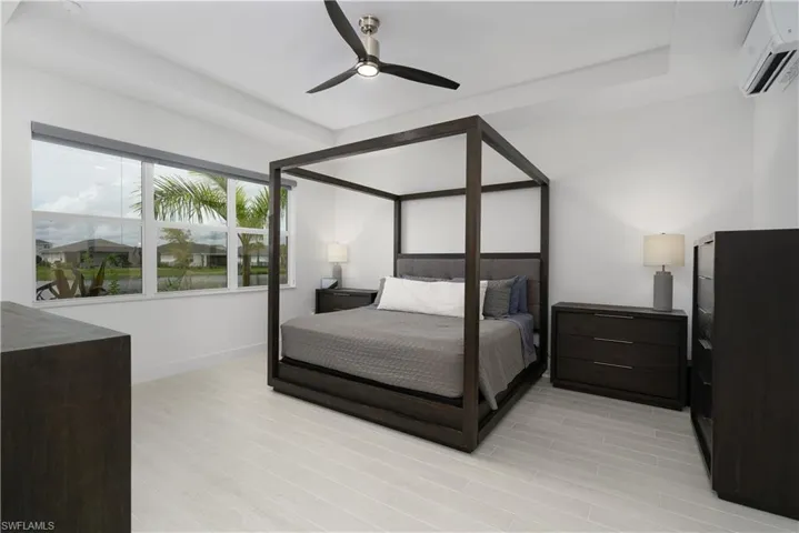 Bedroom featuring a wall mounted air conditioner, light wood finished floors, and a ceiling fan