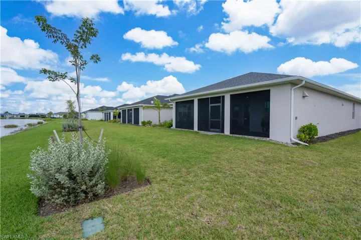 Rear view of property with a yard, a sunroom, and stucco siding