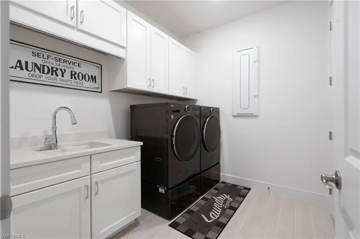 Laundry room with cabinet space, washer and dryer, electric panel, and light wood-type flooring