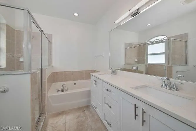 Bathroom with vanity, tile patterned flooring, and shower with separate bathtub
