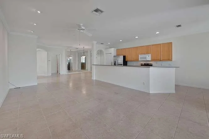Kitchen featuring appliances with stainless steel finishes, light tile patterned floors, crown molding, and ceiling fan