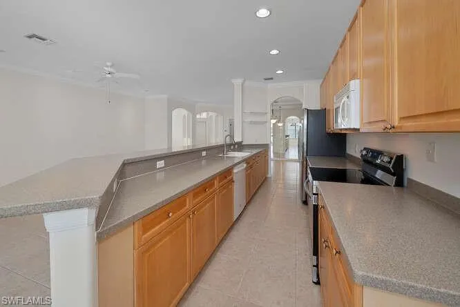 Kitchen featuring a kitchen island with sink, light tile patterned floors, stainless steel appliances, sink, and ceiling fan