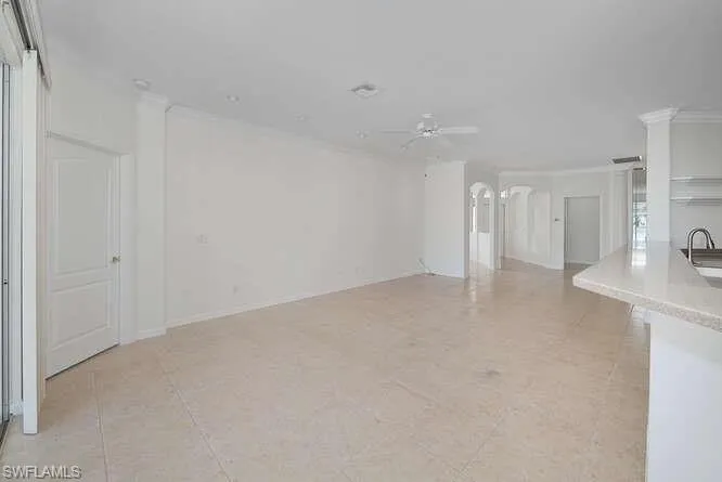 Unfurnished living room with ceiling fan, ornamental molding, sink, and light tile patterned flooring