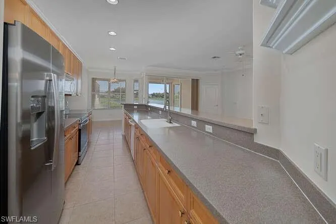 Kitchen with crown molding, sink, ceiling fan, appliances with stainless steel finishes, and light tile patterned flooring