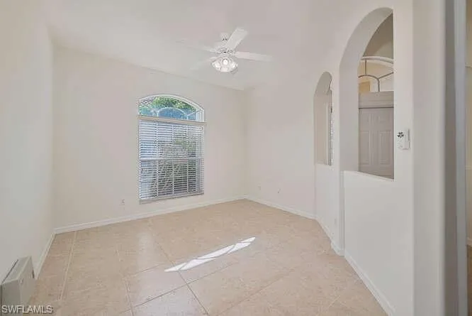 Tiled spare room featuring ceiling fan
