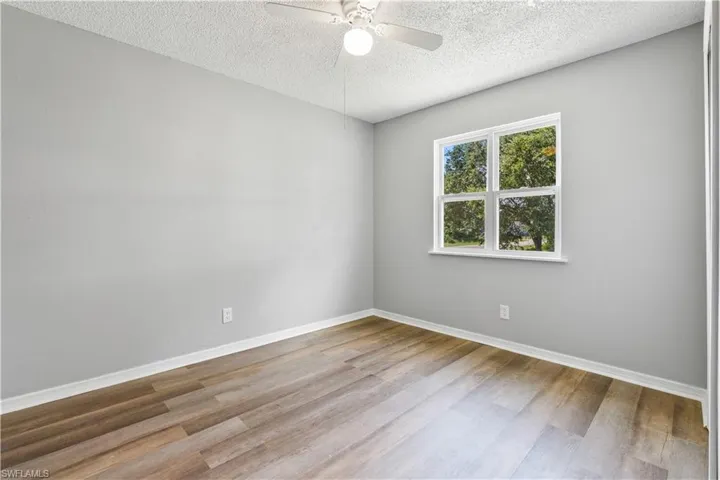 Spare room with wood finished floors, a textured ceiling, and ceiling fan