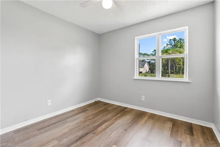 Unfurnished room with wood finished floors, ceiling fan, and a textured ceiling