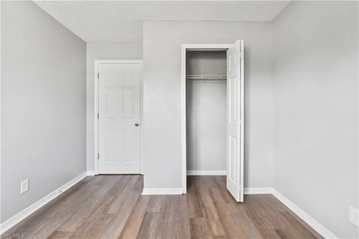 Unfurnished bedroom with wood finished floors, a closet, and a textured ceiling