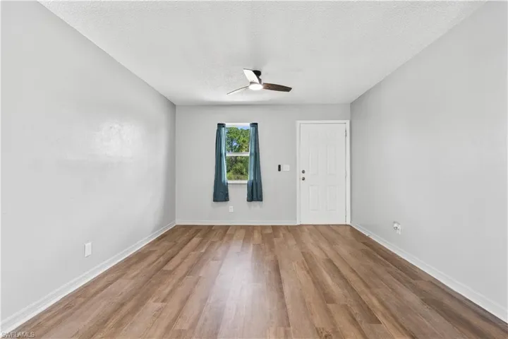 Empty room featuring wood finished floors, a ceiling fan, and a textured ceiling