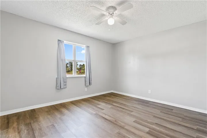 Spare room featuring wood finished floors, a ceiling fan, and a textured ceiling