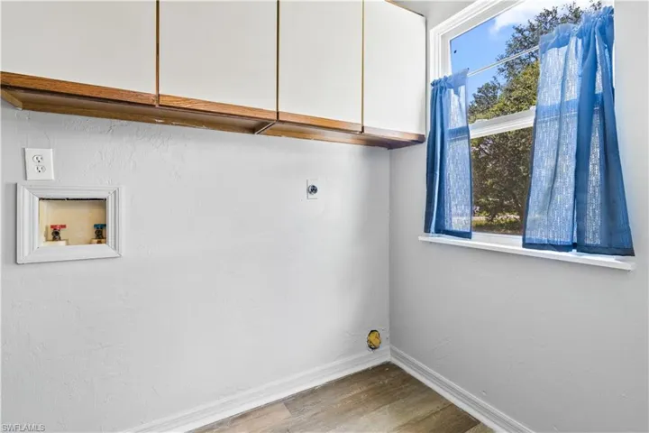 Washroom featuring electric dryer hookup, cabinet space, washer hookup, and wood finished floors