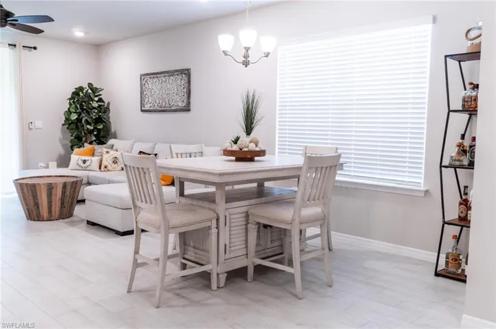 Dining room with ceiling fan with notable chandelier and light hardwood / wood-style floors
