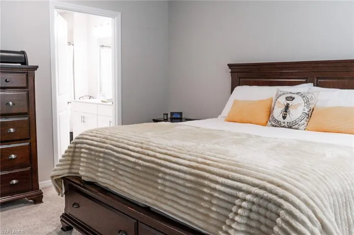 Bedroom featuring ensuite bath and light colored carpet