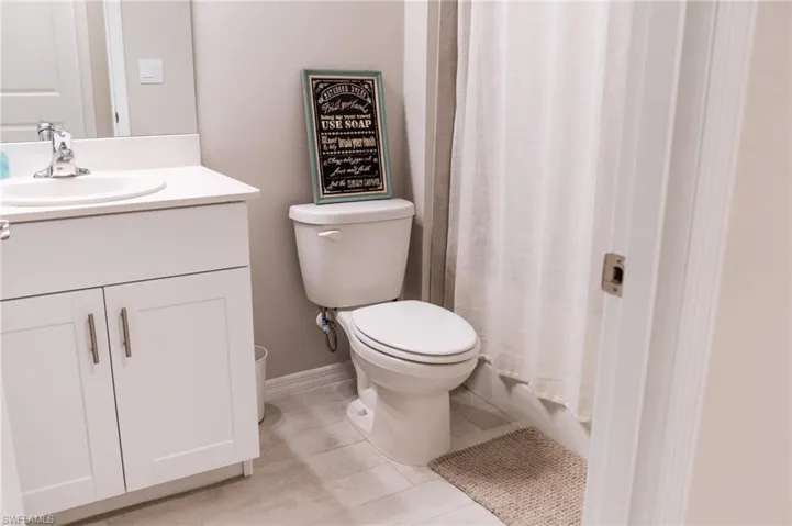 Bathroom with walk in shower, vanity, toilet, and tile patterned floors