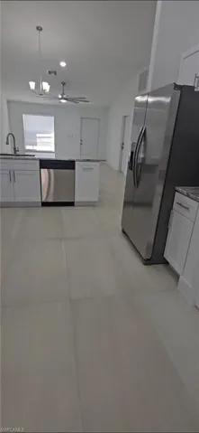 Kitchen with white cabinetry, stainless steel appliances, a chandelier, dark stone countertops, and a ceiling fan