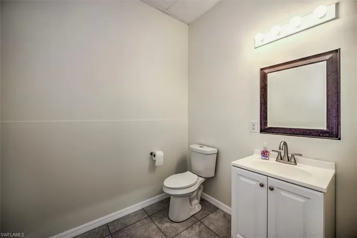 Bathroom with baseboards, vanity, toilet, and tile patterned floors