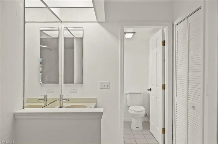 Bathroom with a closet, vanity, and light tile patterned floors