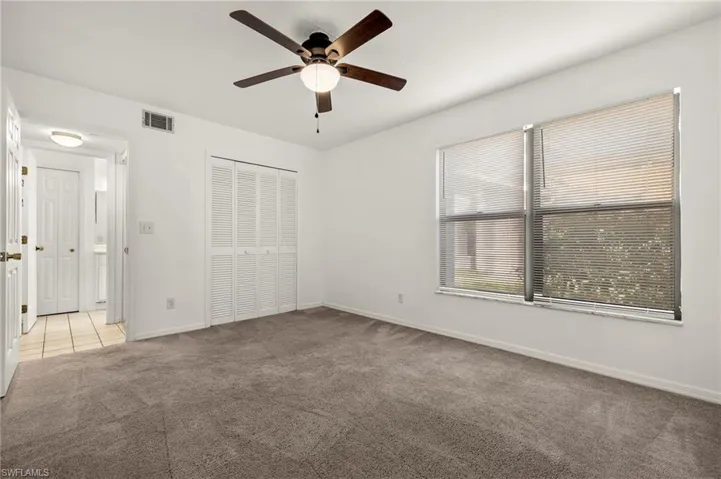 Unfurnished bedroom featuring carpet flooring, a closet, and a ceiling fan