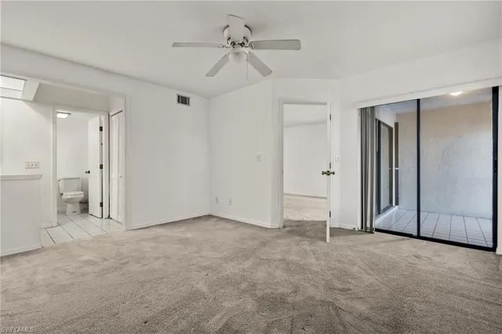 Unfurnished bedroom with light carpet, access to exterior, ceiling fan, and ensuite bathroom