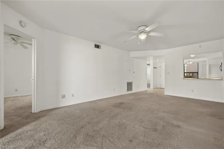Unfurnished living room featuring a ceiling fan and carpet