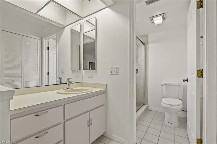 Full bath featuring vanity, a closet, a stall shower, and light tile patterned floors