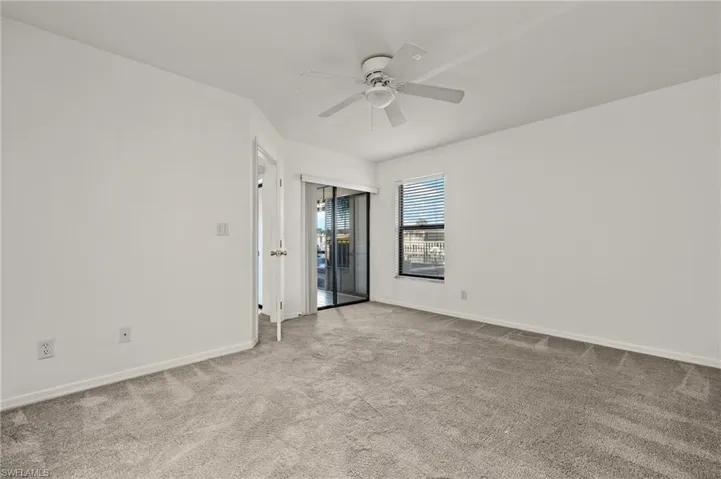 Empty room featuring light colored carpet and a ceiling fan
