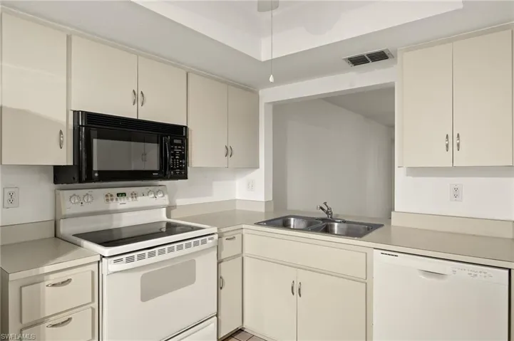 Kitchen with white appliances, light countertops, and cream cabinets
