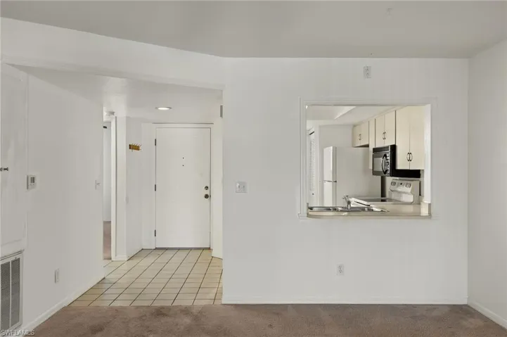 Kitchen featuring light colored carpet, white appliances, light countertops, light tile patterned floors, and a peninsula