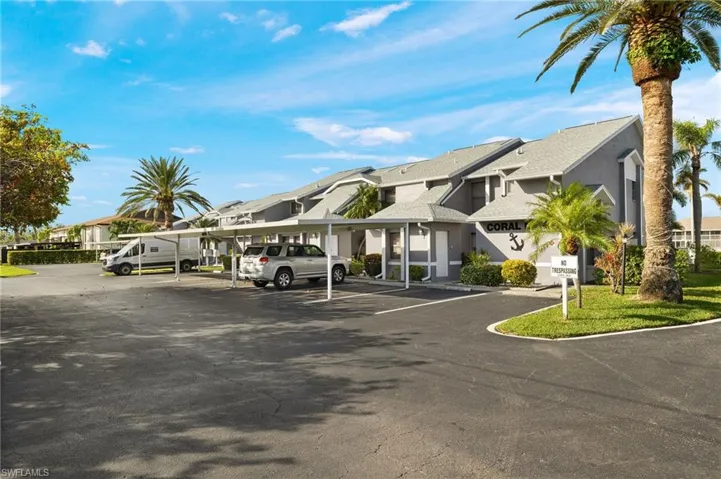 View of property featuring covered and uncovered parking and a residential view