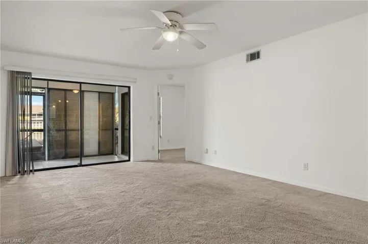 Carpeted empty room featuring ceiling fan and baseboards