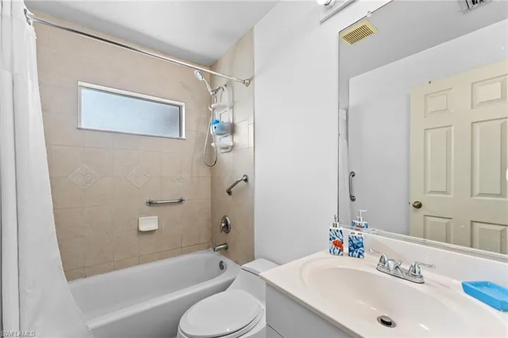 Full bathroom with toilet, vanity, and shower / bath combo with shower curtain