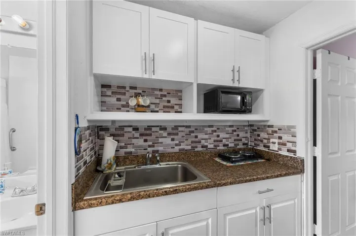 Kitchen with white cabinets, sink, and decorative backsplash