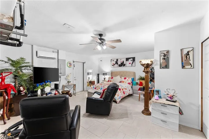 Tiled bedroom with ceiling fan and an AC wall unit