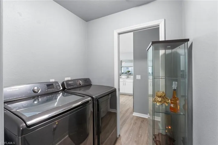 Washroom with washer and dryer and light hardwood / wood-style flooring