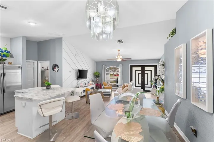 Dining area with lofted ceiling, ceiling fan with notable chandelier, and light hardwood / wood-style flooring
