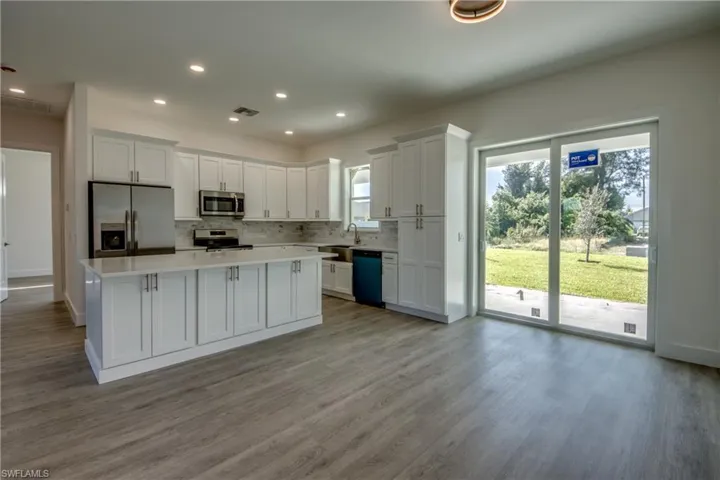 Kitchen with white cabinets, appliances with stainless steel finishes, tasteful backsplash, a center island, and recessed lighting