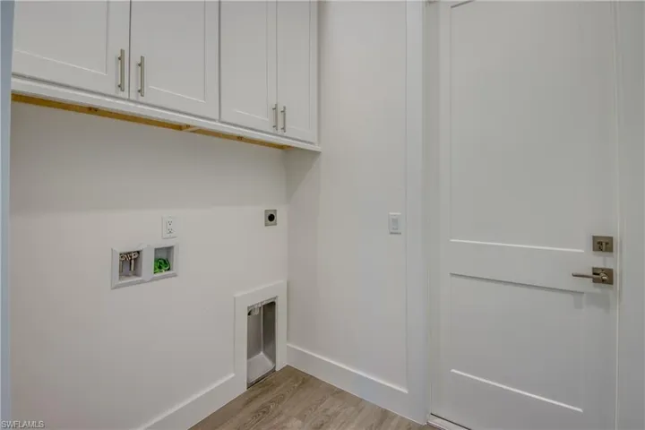 Laundry room with light wood-style flooring, hookup for a washing machine, cabinet space, and hookup for an electric dryer