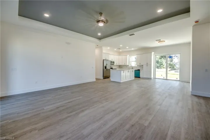 Unfurnished living room with a tray ceiling, recessed lighting, and light wood finished floors