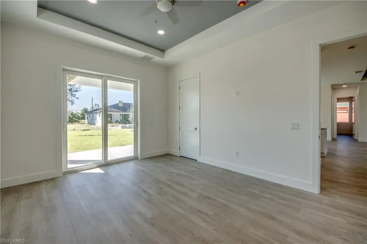 Spare room with light wood-style floors, a tray ceiling, ceiling fan, and recessed lighting