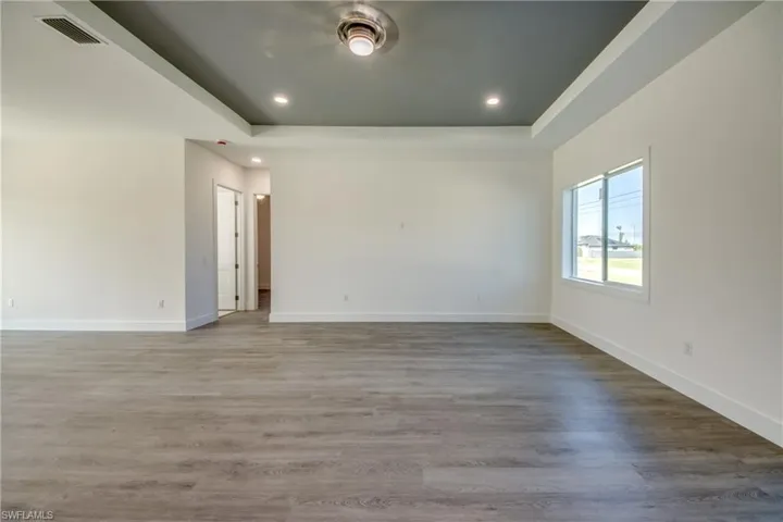 Unfurnished room featuring recessed lighting, a tray ceiling, light wood finished floors, and a ceiling fan