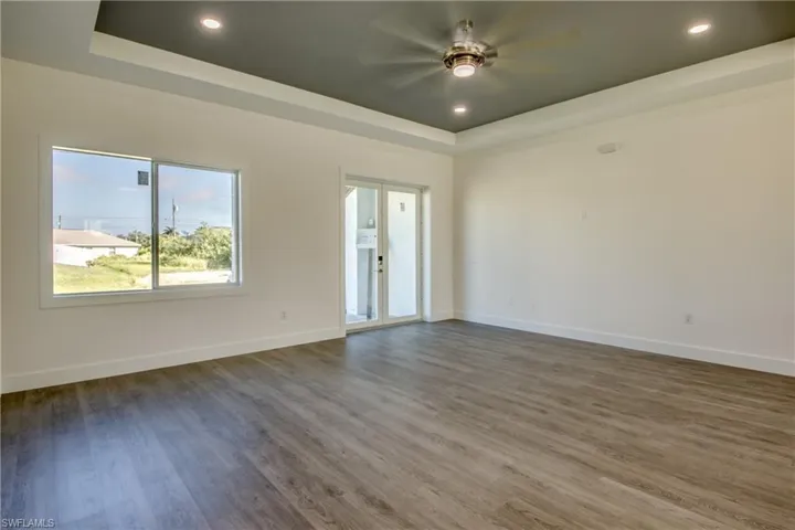 Spare room with a raised ceiling, wood finished floors, recessed lighting, and a ceiling fan