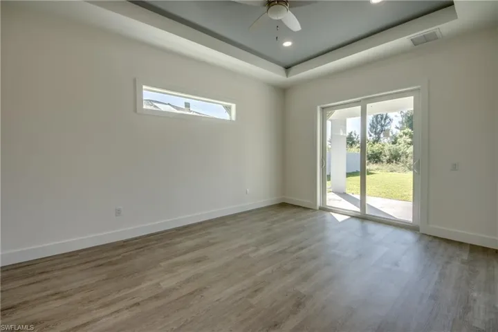 Empty room with light wood-style floors, a tray ceiling, recessed lighting, and ceiling fan