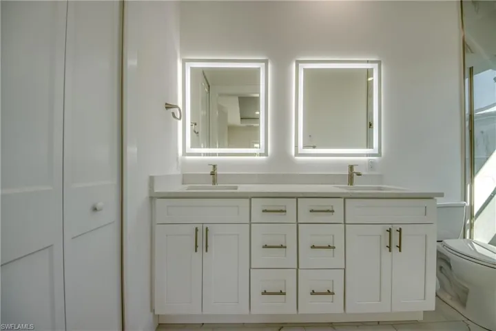 Bathroom featuring double vanity, a stall shower, a closet, and light tile patterned floors